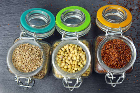 Aromatic spices of coriander seeds, mustard seeds and carom seeds in glass jars on a grey background.の写真素材
