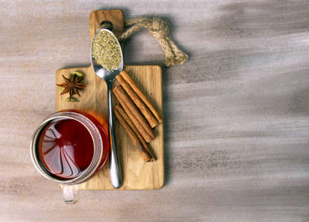 A cup of tea with spices on a wooden board copy space on a wooden background.の写真素材