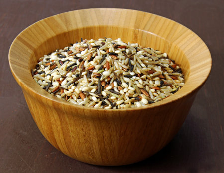 A wooden bowl on wild rice on a moody background, selective focus.
