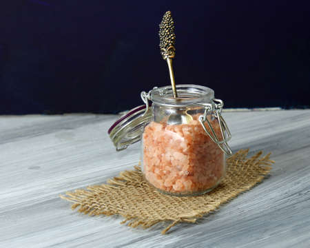 A jar of Himalayan salt in a jar with a spoon on a wooden baackground.の写真素材