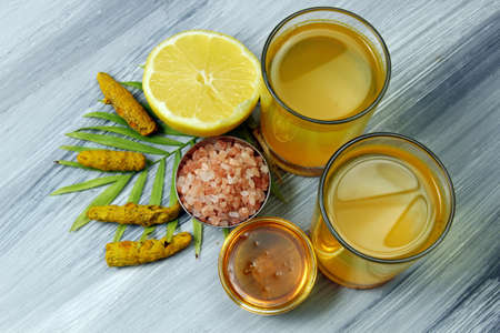 Spicy healthy Haldi or Turmeric, lemon, Himalayan salt and Honey antioxidant drink with lemon on a moody background.の写真素材