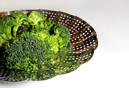 Fresh Brocolli florets in a steamer strainer with copy space on a white background, selective focus.の写真素材