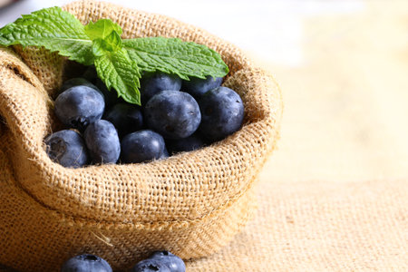 Blueberries with mint leaves in a burlap bag with copy space, selective focusの写真素材