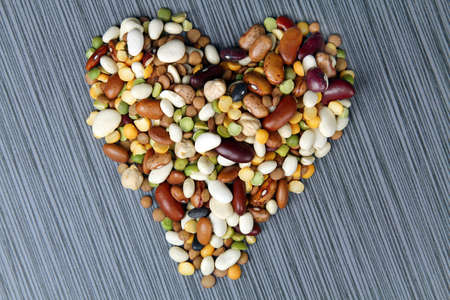 All kinds of beans in the shape of heart on a grey stone backgroundの写真素材