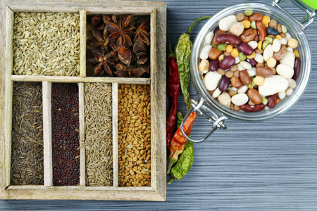 Indian spices in the spice box on a stone background with dried red chili pepers, selective focus.