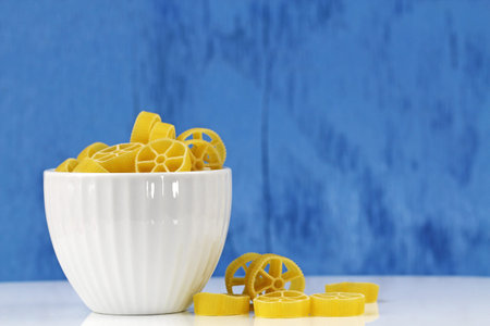 A bowl of cavatappi pasta on a blue bakground, selective focus with copy space.の写真素材