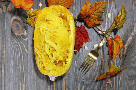 Overhead view of Spaghetti squash on a wooden background with fall leavesの写真素材
