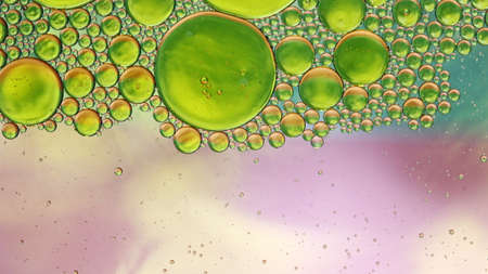 Green oil in water globules on pink background abstractの写真素材