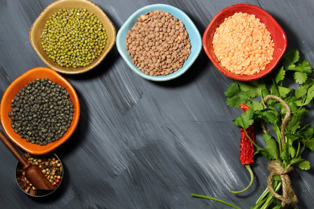 Different types of lentils in  bowls (yellow, brown, green, red, french green, black lentils) with...