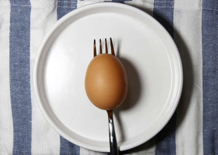 A brown egg on a plate on a striped backgroundの写真素材