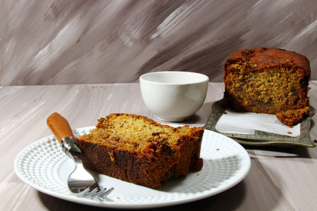 A slice of Banana bread with dates and chocolate chips on a tray on a wooden background, copyspace.の写真素材
