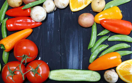 Top view of  vegetables like tomatoes, potatoes, peas, peppers, cabbage and mushrooms with copy space in the centerの写真素材
