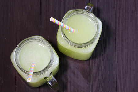 Two mason Jars with fresh lemonade on a dark moody wooden background. Top view.