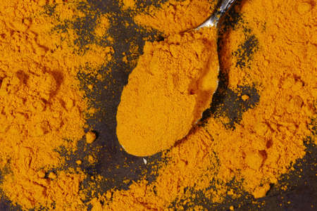 A spoonful of yellow Turmeric powder on a metal backgroundの写真素材