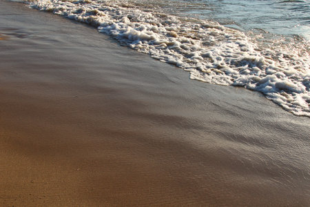 A background of a sandy beach with a receding wave