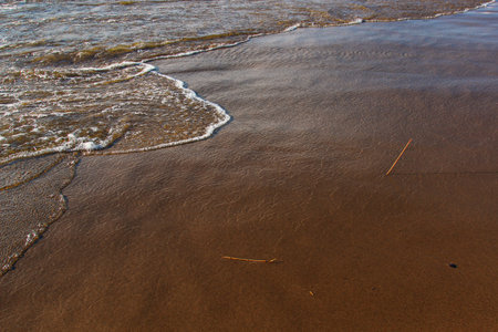 A background of a sandy beach with a receding waveの写真素材