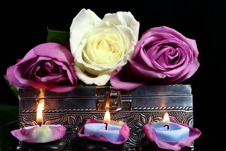 Lighted candles with a metal box and rose petalsの写真素材