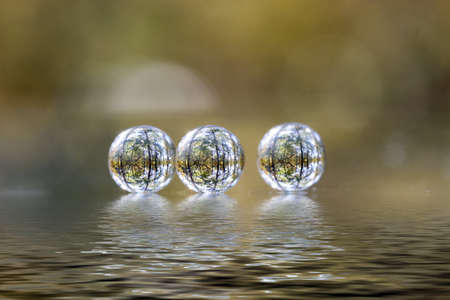 Three transparent balls and their reflection with refraction of nature around.の写真素材