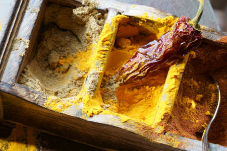 Close up of Indian spices of Turmeric powder, coriander powder and chili powder in  a wooden box with a spoon.の写真素材