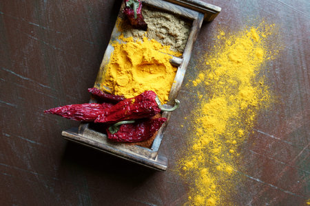 Close up of Indian spices of Turmeric powder, coriander powder and chili powder in  a wooden box with a spoon.の写真素材