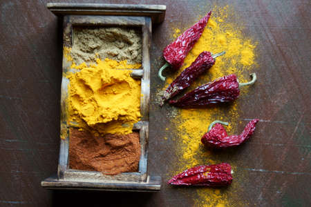 Close up of Indian spices of Turmeric powder, coriander powder and chili powder in  a wooden box with a spoon.の写真素材