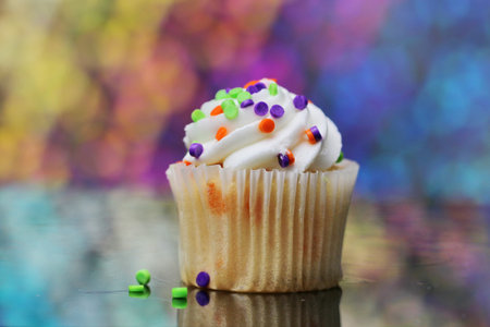 Three cup cakes with selective focus and a colorful bokeh.