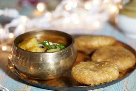 A plate of Khasta Kachauri with a bowl of spicy and tangy Potato sabji or curry.
