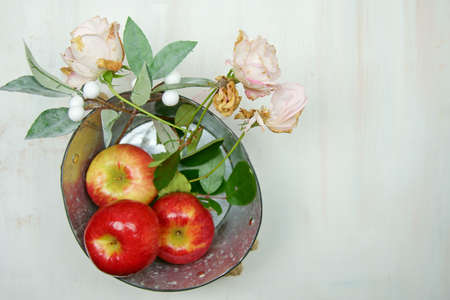 Overhead view of red apples in a tin with rose flowers.の写真素材