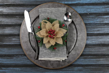 Overhead view of  table setting - a plate with spoon, fork and knife with a Christmas decoration on a wooden background.の写真素材