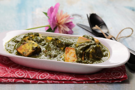 A bowl of Palak Paneer made of Paneer cheese dipped in mildly spiced Spinach gravy on wooden...