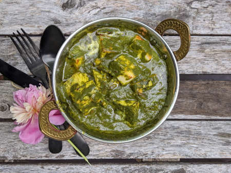 A bowl of Palak Paneer made of Paneer cheese dipped in mildly spiced Spinach gravy on wooden background.の写真素材
