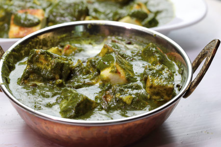 A bowl of Palak Paneer made of Paneer cheese dipped in mildly spiced Spinach gravy on wooden...