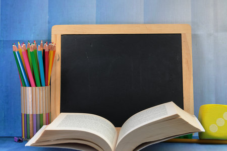 A black board with copy space and school supplies and a book. Back to school concept.