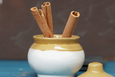 Cinnamon sticks in a container on a blue wooden backgroundの写真素材