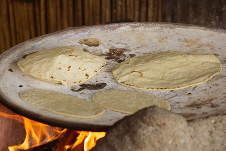 Organic Mexican tortilla cooked on a clay comal directly on the fire. Traditional mexican meal.の写真素材