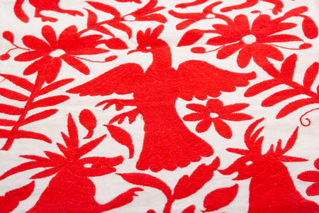 Closeup of red flower pattern on white fabric background with red bird. I have textile. embroidered fabric with animal figures from an ethnic group of Hidalgo, Mexico.の写真素材
