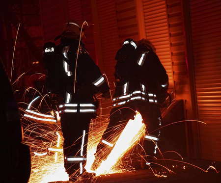 Nightly firefighters; cutting a door の写真素材