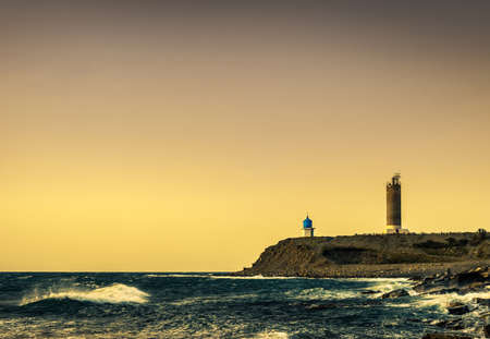 lighthouse and small church at stormy sunsetの写真素材