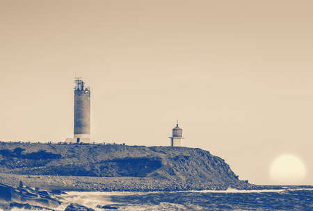 lighthouse and church at stormy sunsetの写真素材