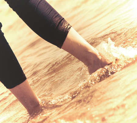 female legs in sunny waterの写真素材