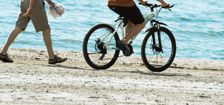 biker and pedestrian moving along sandy beach