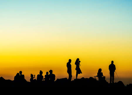 various people at sunset rocky shoreの写真素材
