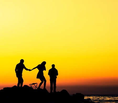 people at the sunset rocky shoreの写真素材