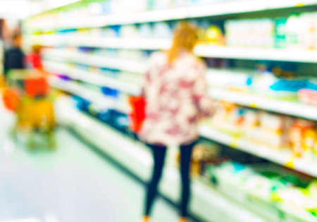 young woman near the dairy racks of supermarketの写真素材