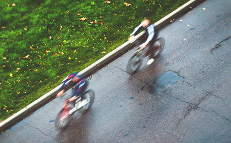 bicyclists ride sport bicycles along autumnal street