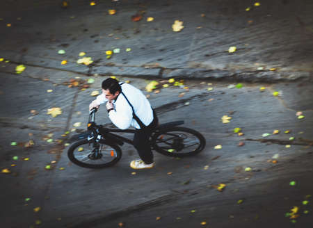 bicyclist rides mountain bike on autumnal streetの写真素材