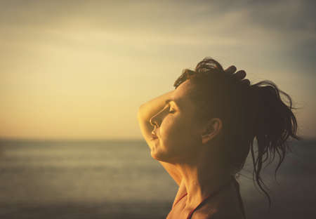 the last sunrays. 45-50 yo brunette woman on sunset beach, retro tones closeup portraitの写真素材