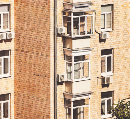 brick apartment building sunny facade with its plastic glazing of windows and balkomies, air...
