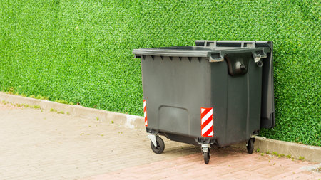 wheeled plastic city dumpster on sidewalkの写真素材