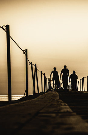 Silhouette of family on the pier at sunsetの写真素材